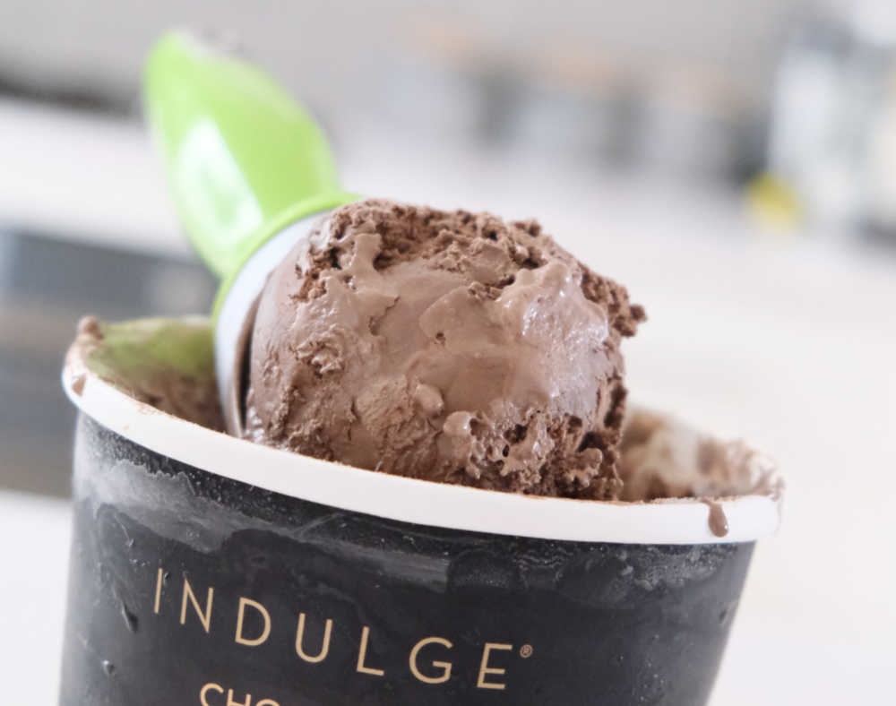A closeup of a scoop of Indulge chocolate resting on the top of the container.