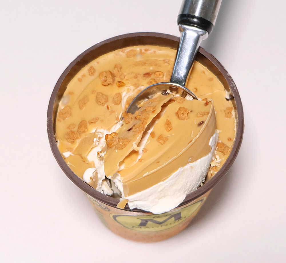 Top down tub of Magnum Luxe Gold Caramelised Chocolate with a scoop driven into the ice cream.