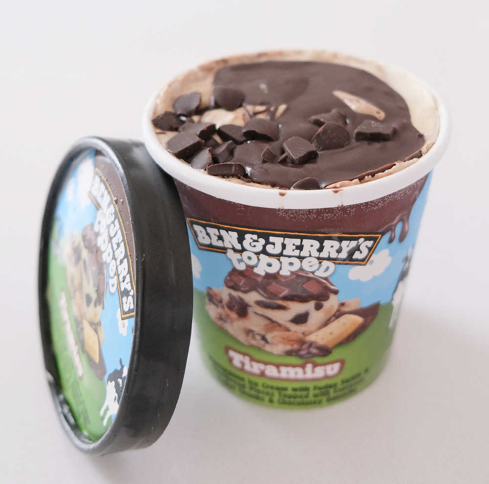 An open container of Ben & Jerry's Topped Tiramisu Ice Cream 436ml on a white kitchen bench.