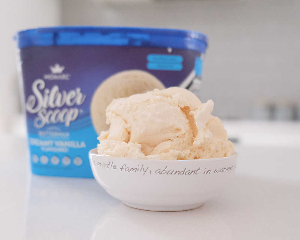 A bowl of Monarc Silver Scoop Vanilla Ice Cream sitting on a kitchen bench with the container in the background.