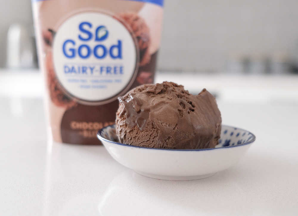 A bowl of So Good Chocolate Ice Cream on the bench with the packaging in the background.