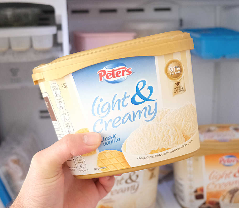 Holding a container of Peters Light & Creamy Classic Vanilla.