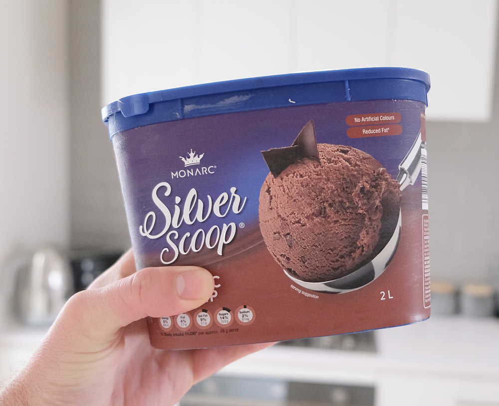 Holding a pack of Monarc Silver Scoop Choc Chip Ice Cream 2L.