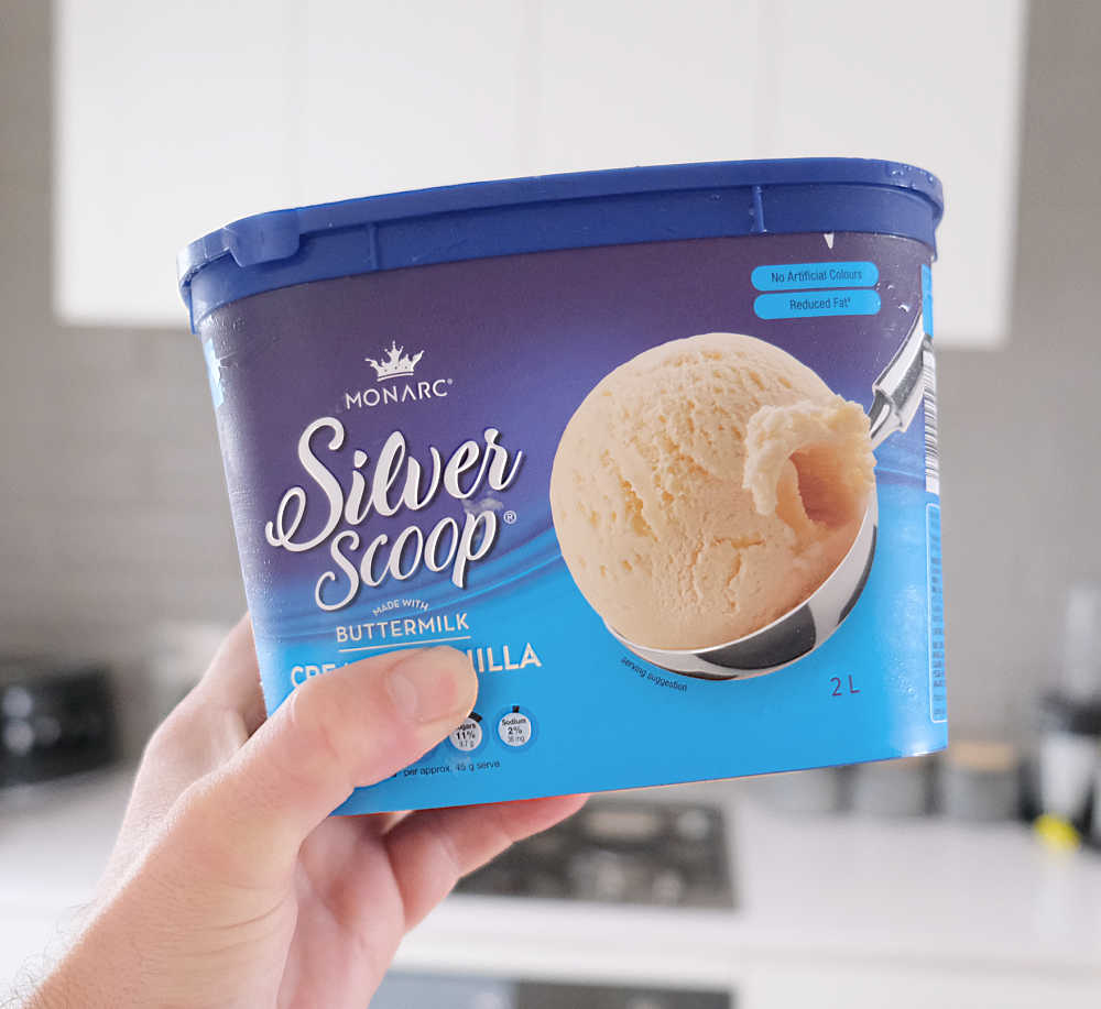 Holding a container of Monarc Ice Cream, Vanilla two litre.