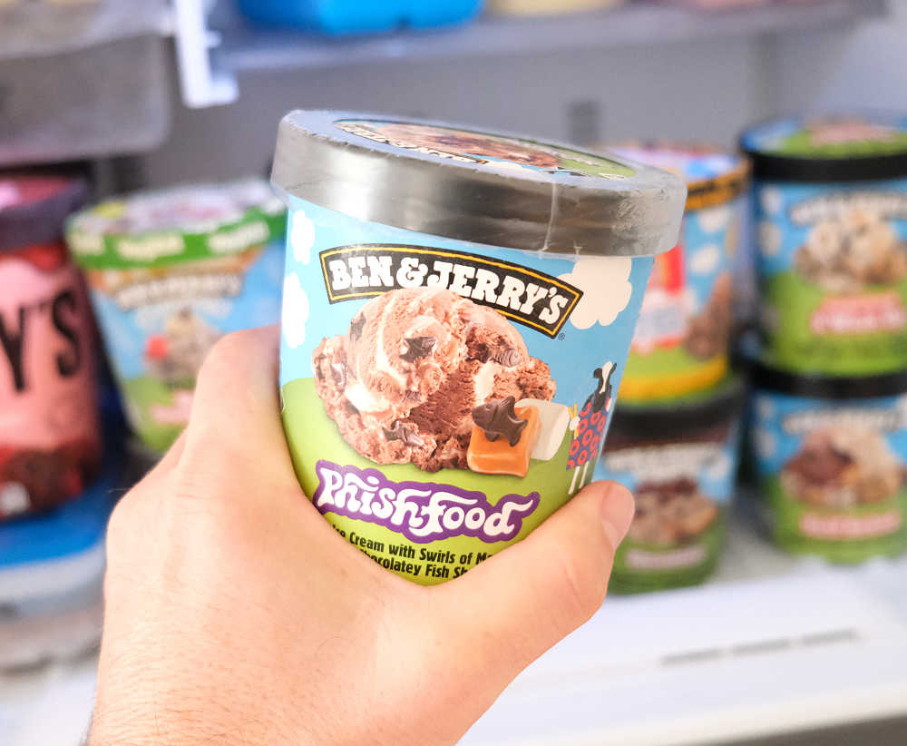 Holding an unopened pack of Ben & Jerry's Phish Food Ice Cream in front of a home freezer.