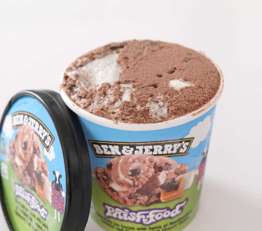 An open container of Ben & Jerry's Phish Food with the lid leaning against the side.