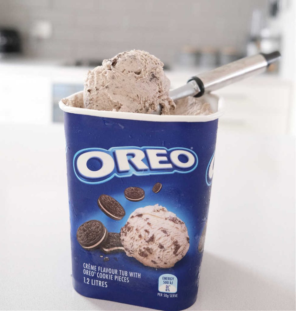 A scoop of Oreo Ice Cream sitting on the top of the container.