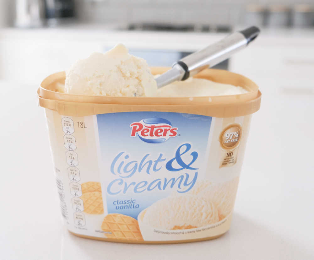 An open container of Peters Light & Creamy Classic Vanilla with the scoop on the top.