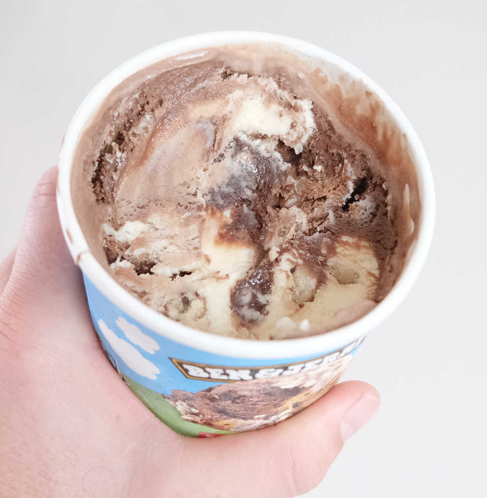 Holding a partly eaten tub of Ben & Jerry's Half Baked Ice Cream 458ml.