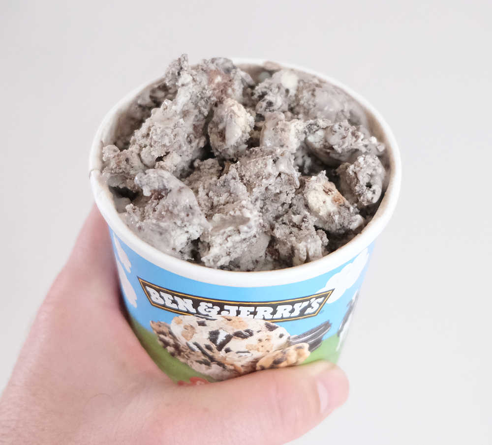 Holding a partly eaten container of Cookie Dough S'Wich Up ice cream by Ben and Jerry's.