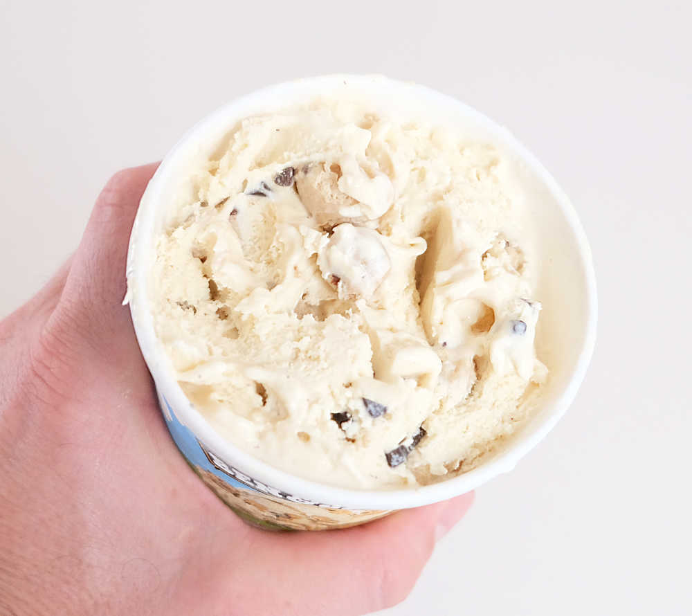 Holding a partly eaten tub of Ben & Jerry's Chocolate Chip Cookie Dough Ice Cream.