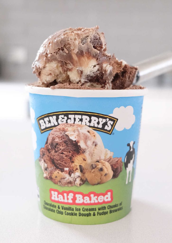 A vertical photo of the Half Baked Ice Cream pack with a scoop resting on the top.