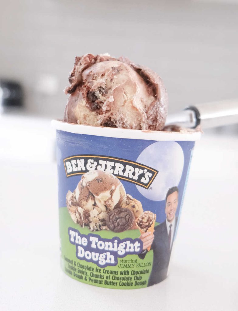 A vertical photo of the Tonight Dough pack and a scoop resting on the top of the tub.