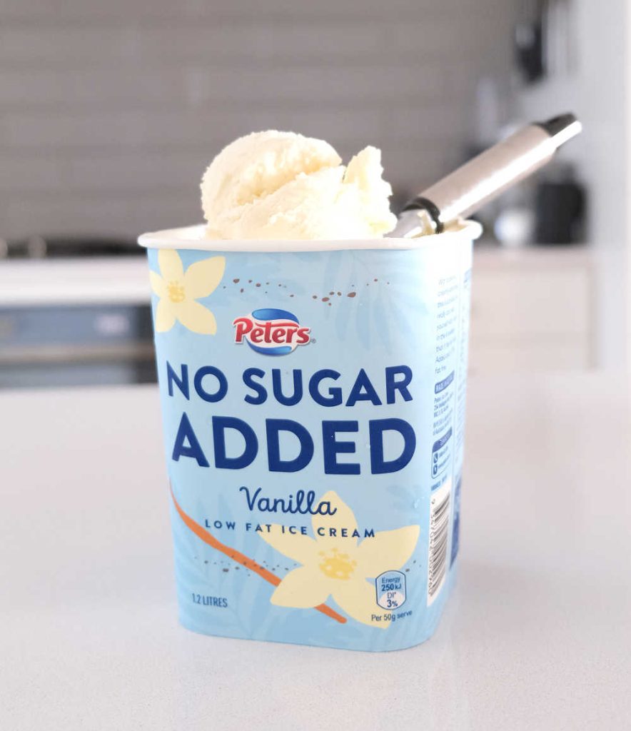 A scoop of Peters No Sugar Added Vanilla 1.2L resting on the top of the container.