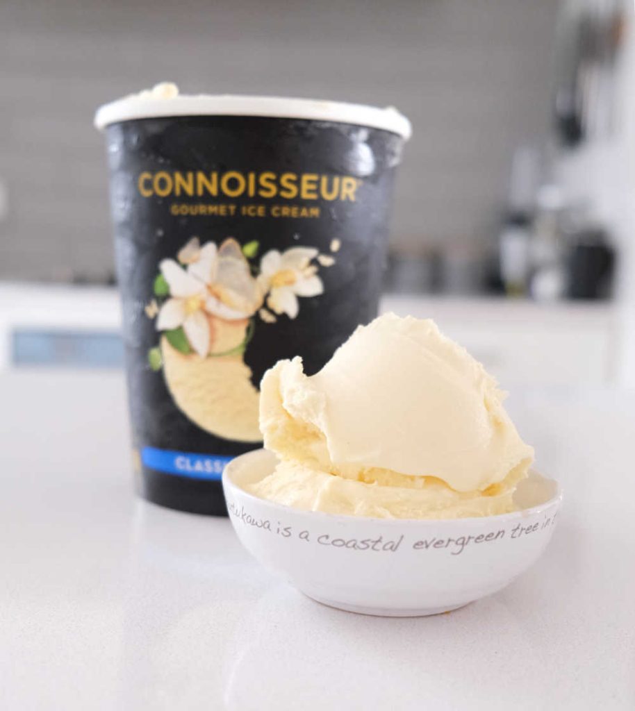 A bowl of vanilla ice cream with the Connoisseur packaging in the background.