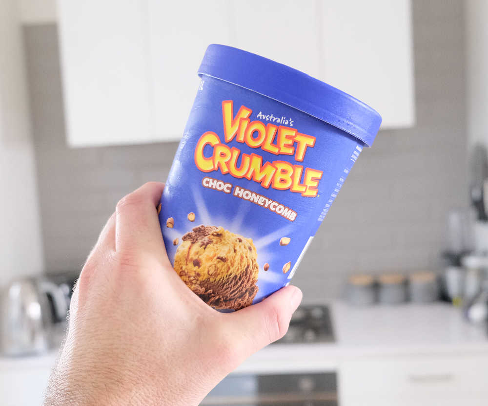 Holding a container of Violet Crumble Choc Honeycomb Ice Cream 1L.