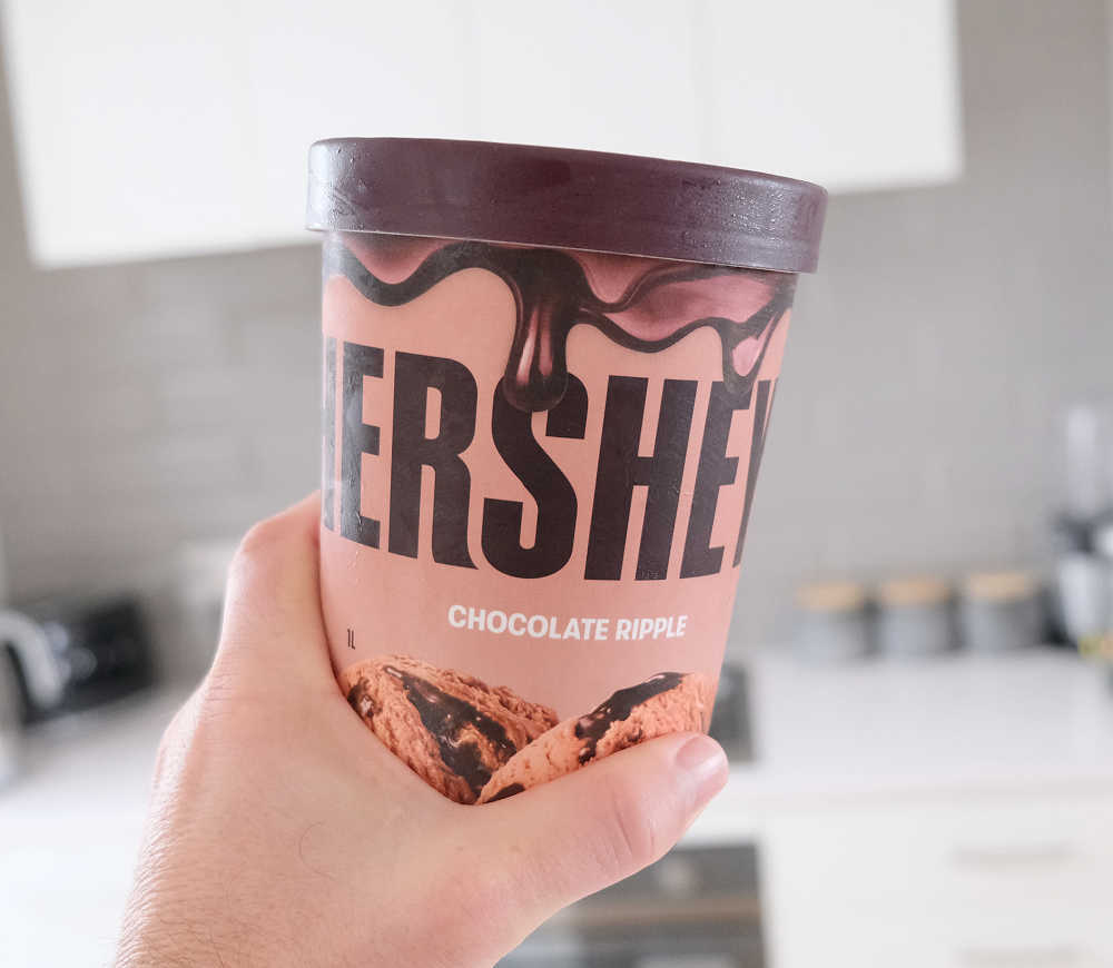 Holding a tub of Hershey's Chocolate Ripple 1L.