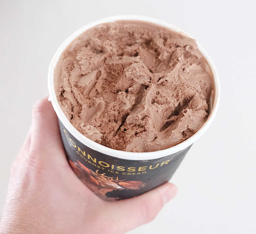Holding a container of Connoisseur Belgian Choc 1L.
