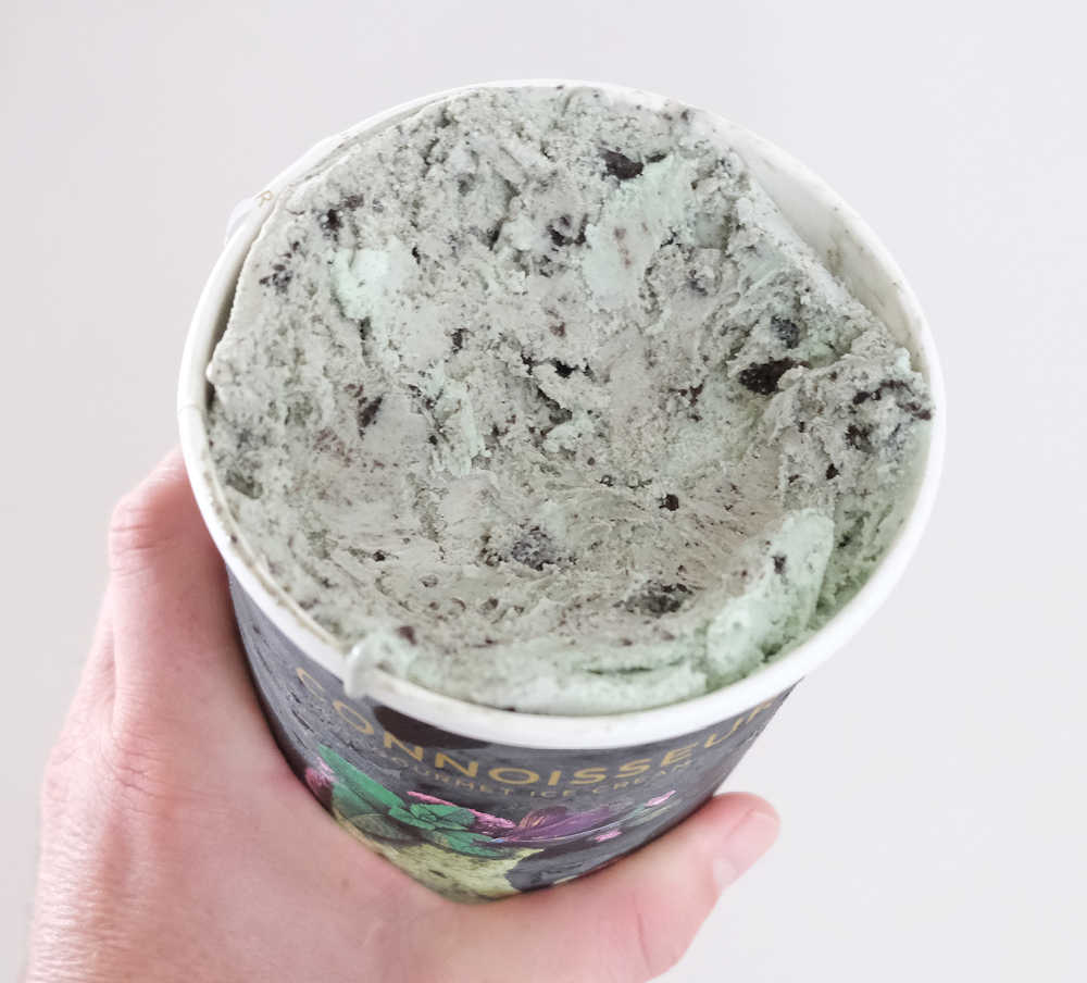 Holding a partly eaten container of Connoisseur Mint & Cookies 1L.
