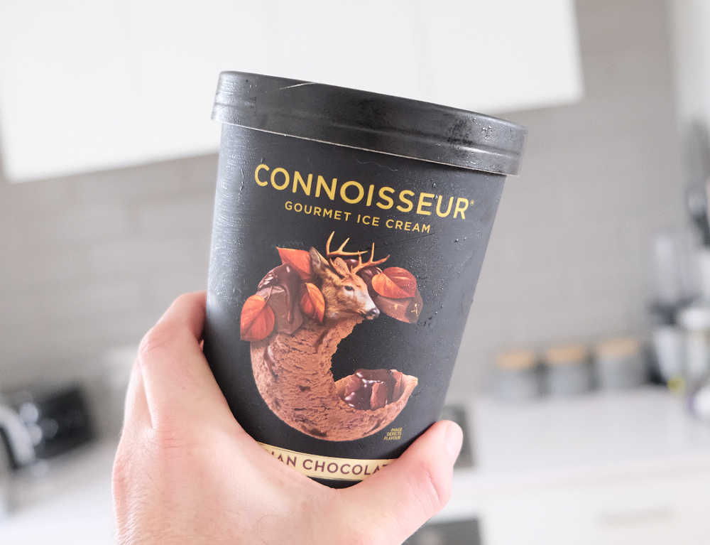 Holding a pack of Connoisseur Gourmet Ice Cream Belgian Chocolate 1L.