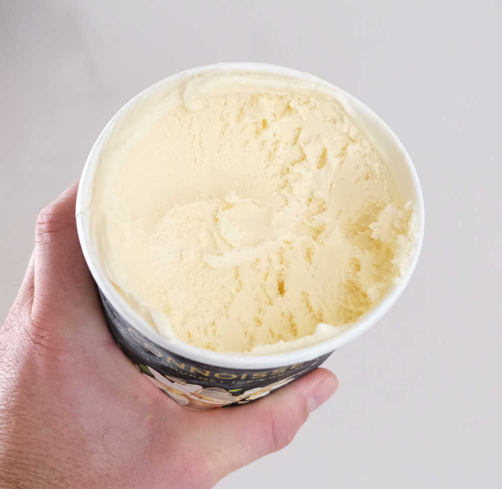 Holding a partly eaten container of Connoisseur Gourmet Ice Cream Classic Vanilla 1L.