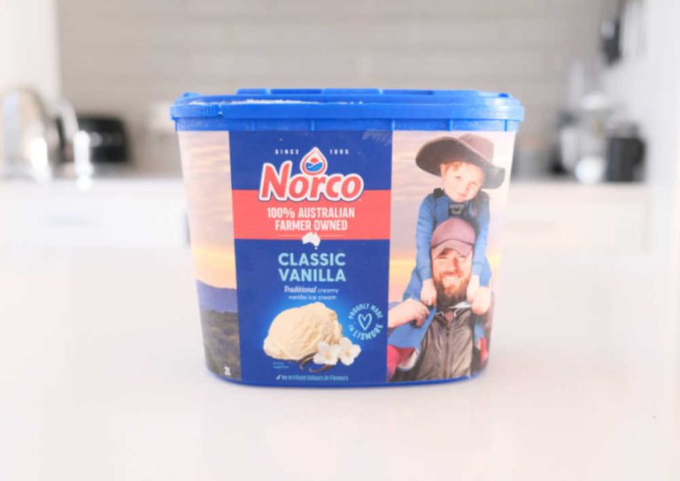 A tub of Norco Classic Vanilla Ice Cream sitting on a kitchen bench.
