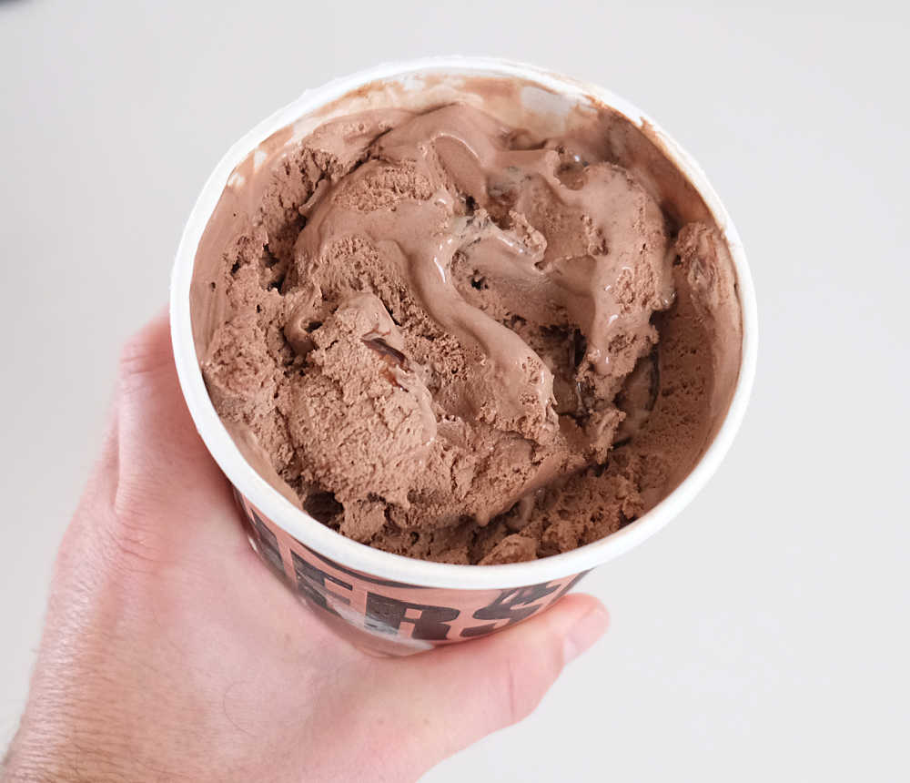 Holding a partly eaten tub of Hershey's Chocolate Ripple 1L.