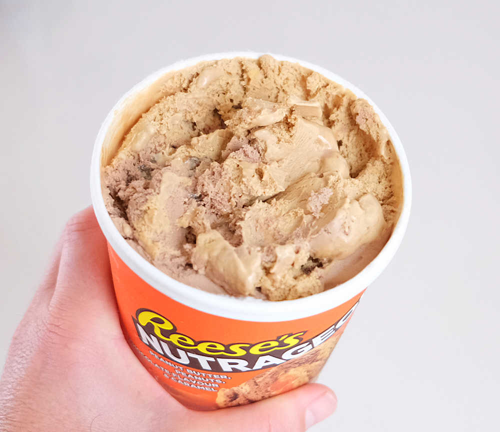 A hand holding a partly eaten pack of Nutrageous low fat ice cream.