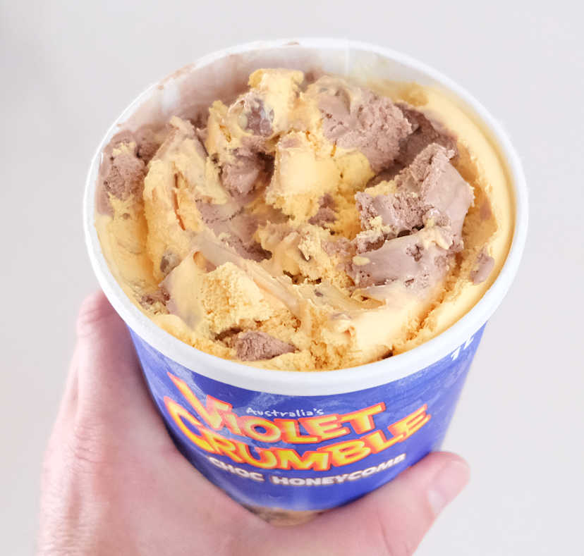 Holding a pack of Violet Crumble 1L.
