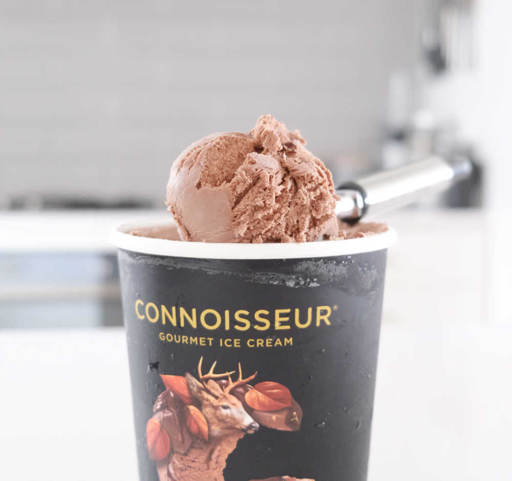 A scoop of Connoisseur Gourmet Ice Cream Belgian Chocolate 1L and the tub in the kitchen.