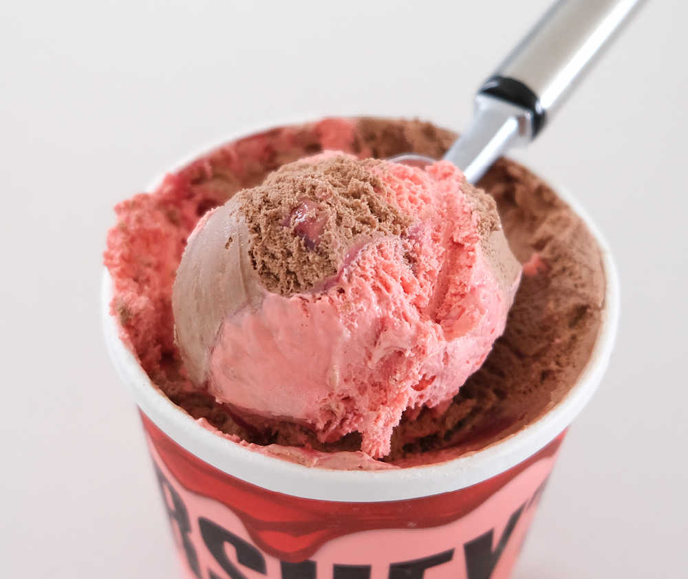 Closeup of a scoop of Hershey's Chocolate-Strawberry Ripple resting on the top of the container.